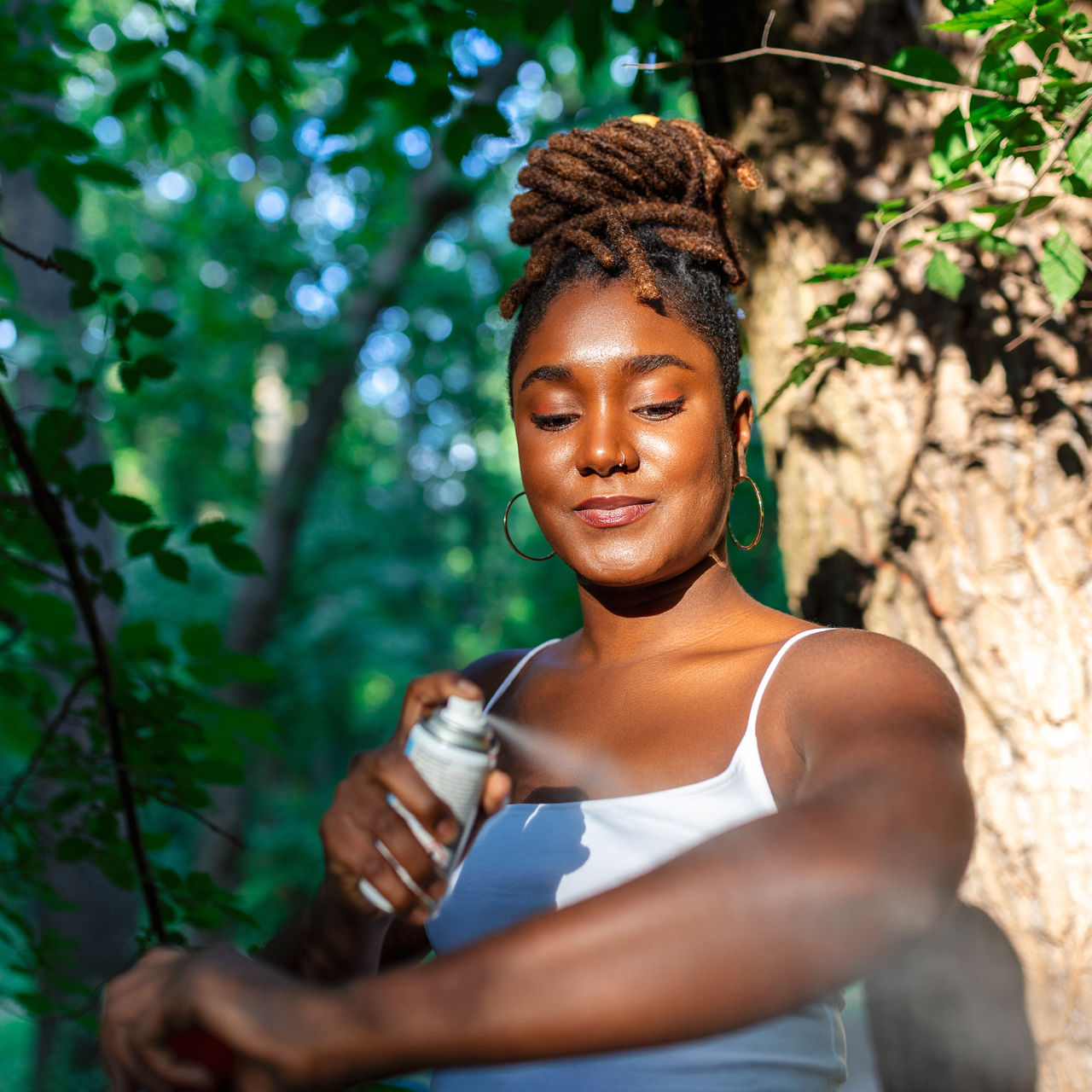 Woman applying insect repellent against mosquito and tick on her arms during hike in nature