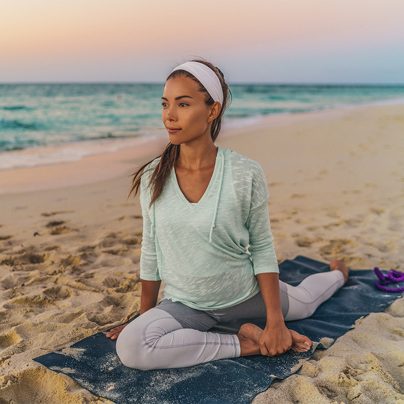 A woman on a yoga mat stretching 