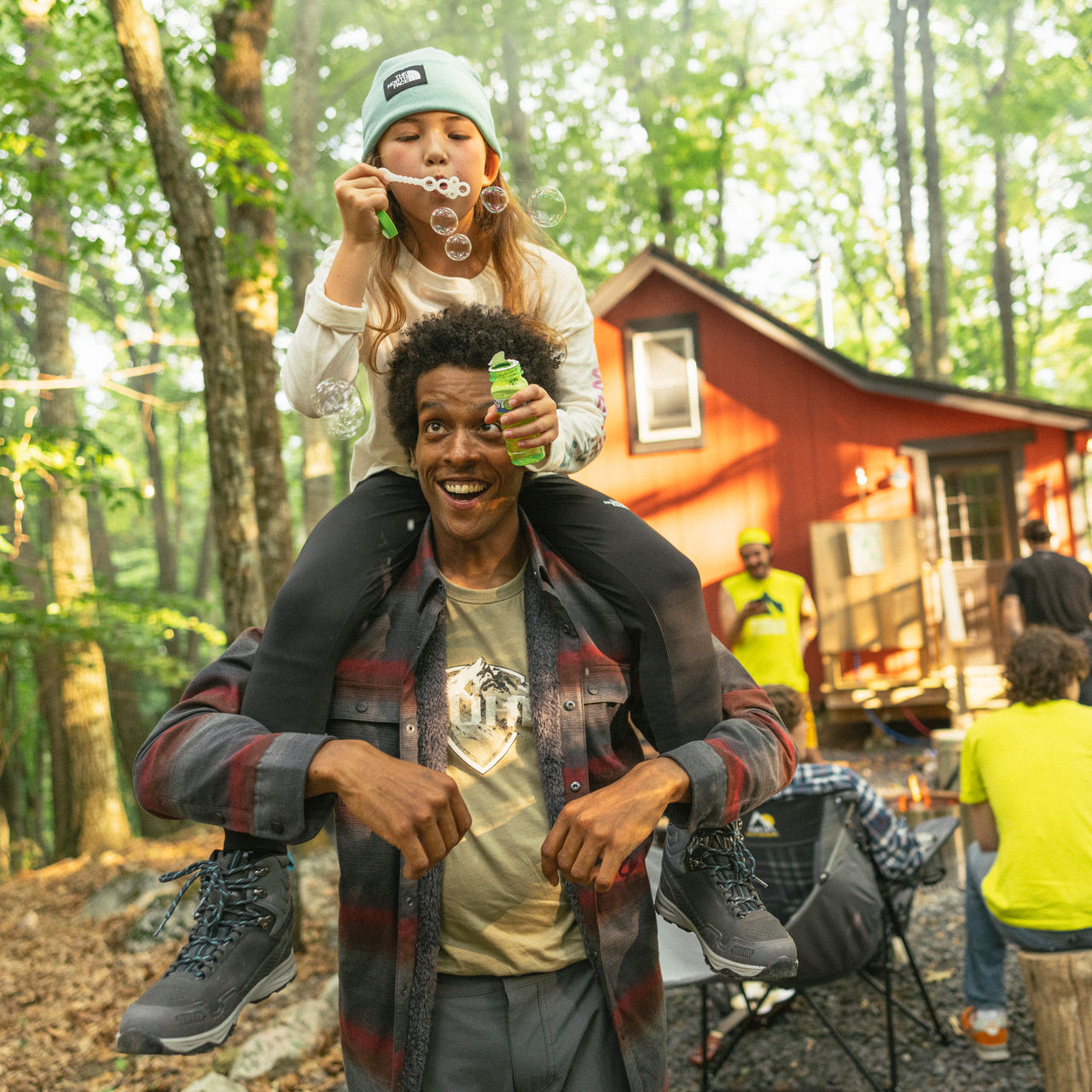 A man and child camp outdoors and blow bubbles