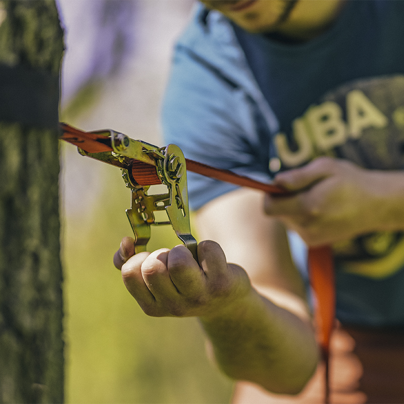 Setting up slacklining equipment and tightening the line on a tree
