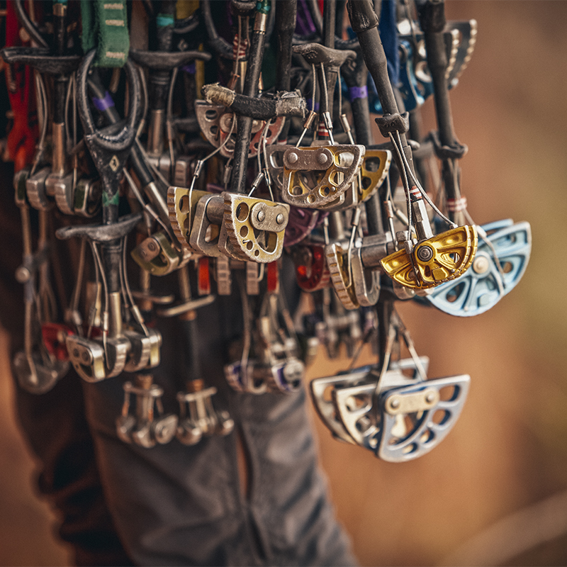 An assortment of trad climbing gear hangs from a climbers harness.