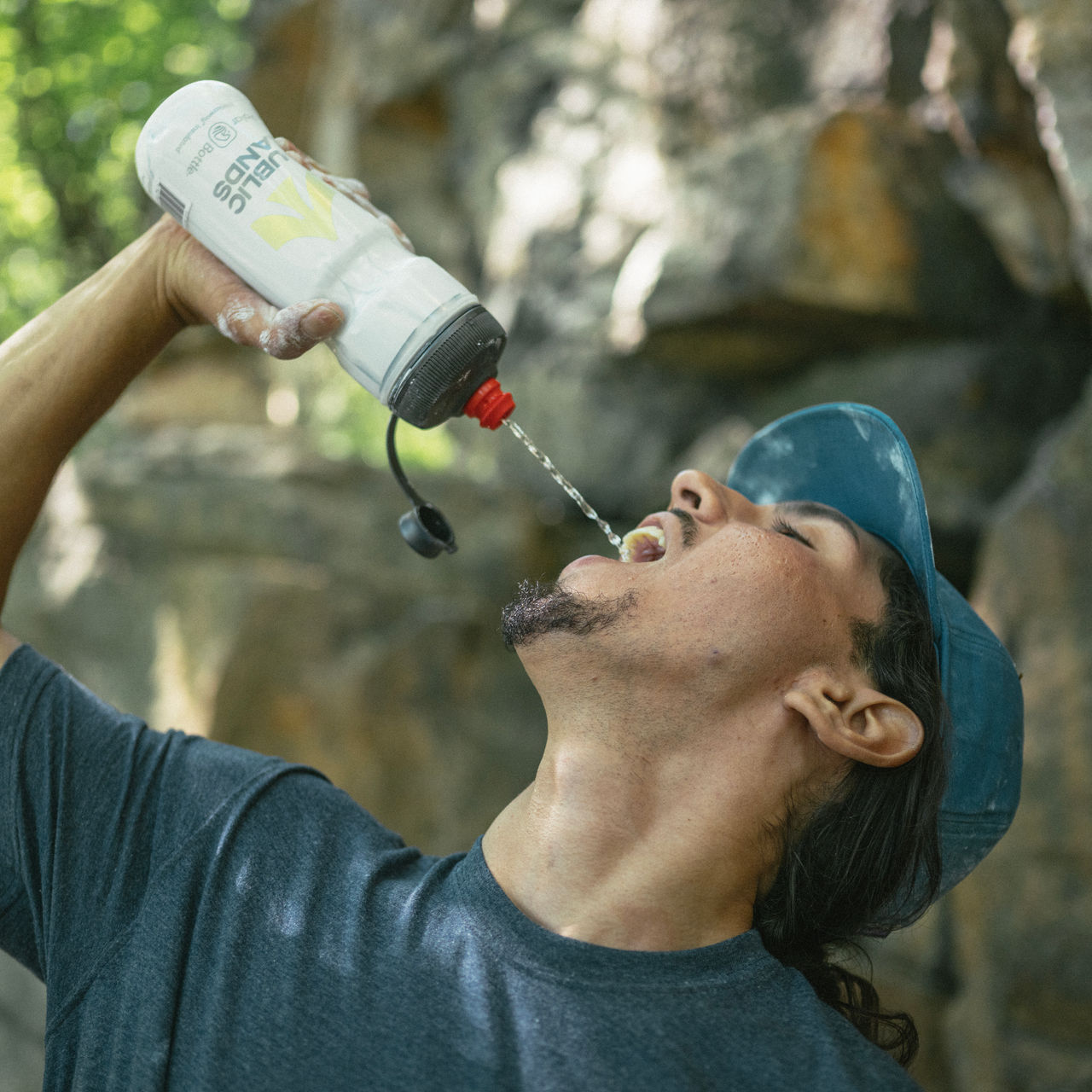 A man drinks water from a water bottle in the summer