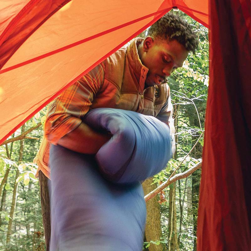 Camper folding a puffy sleeping bag