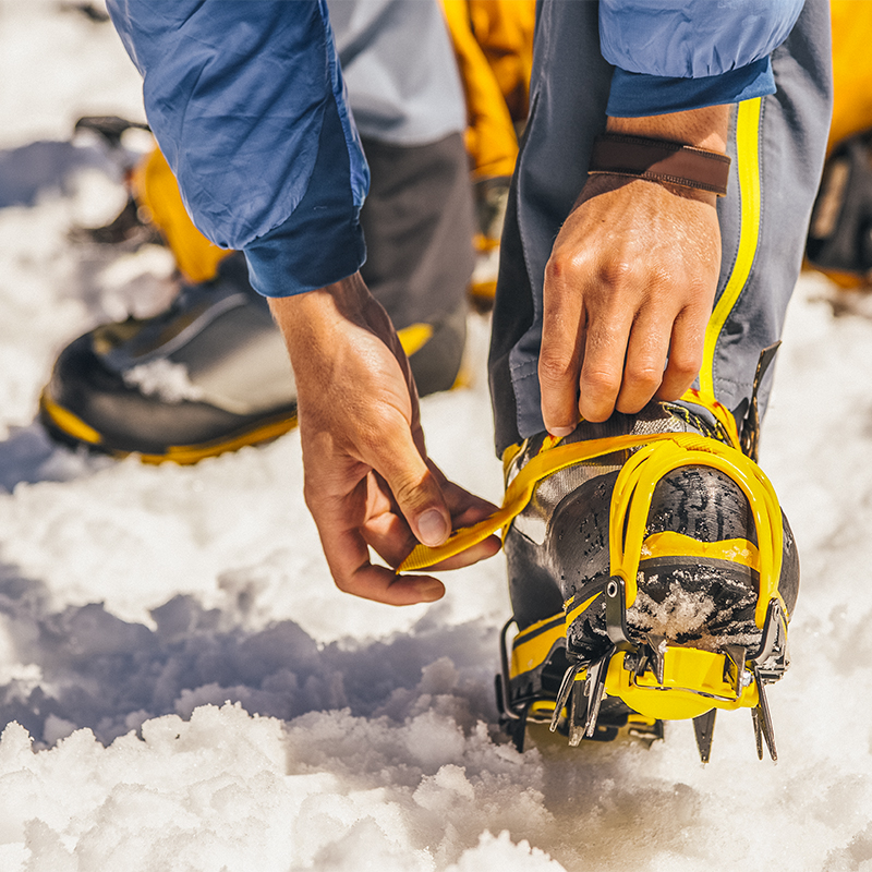 A man dresses climbing Crampons over shoes