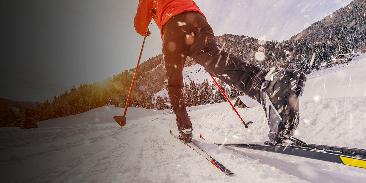 Man cross-country skiing during sunny winter day.