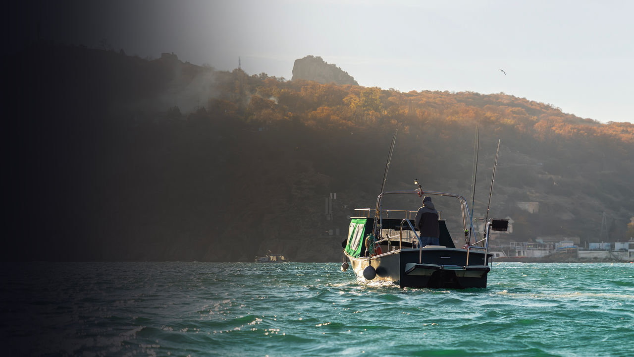 Fishing speedboat with angling man at foggy bay