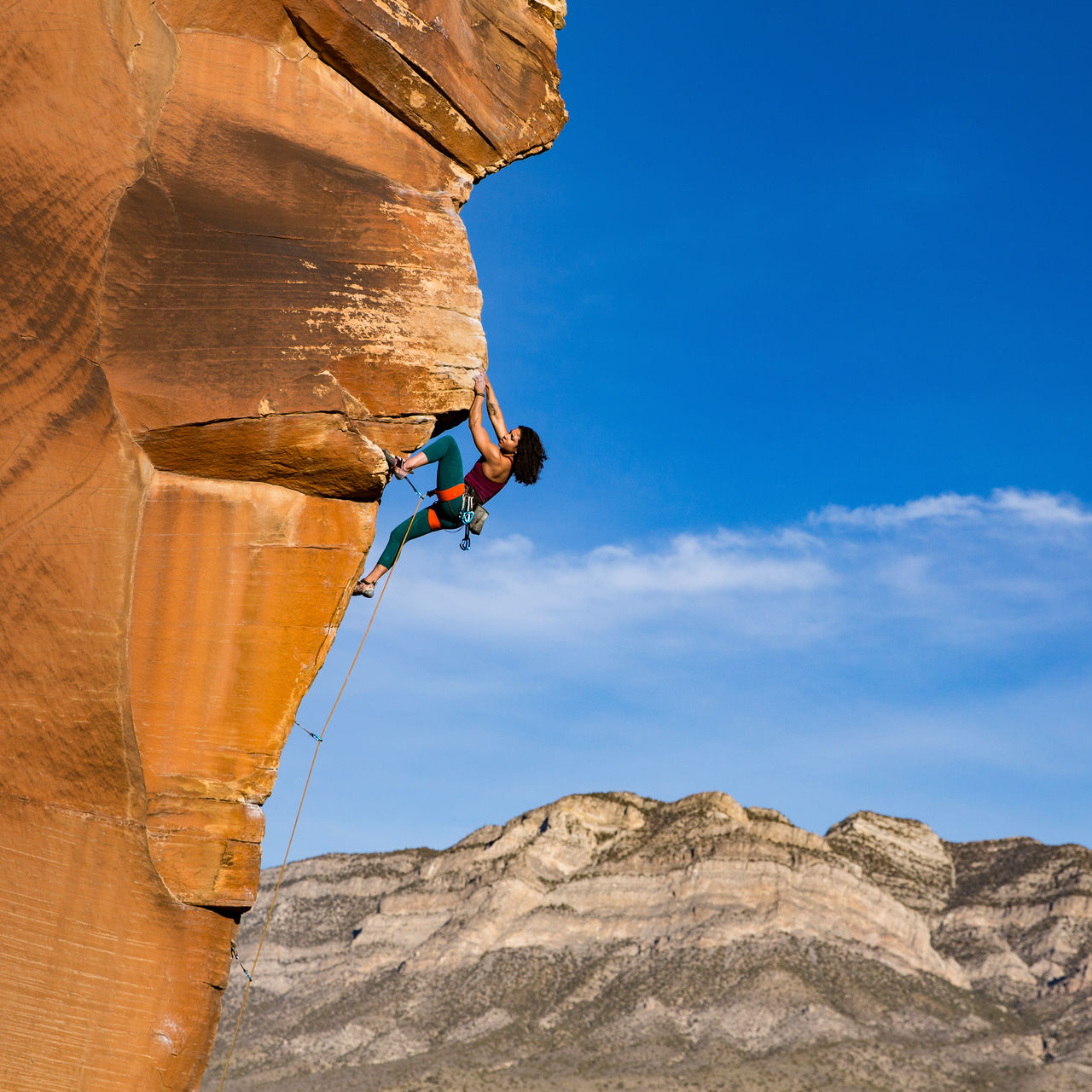A woman rock climbs on a steep wall