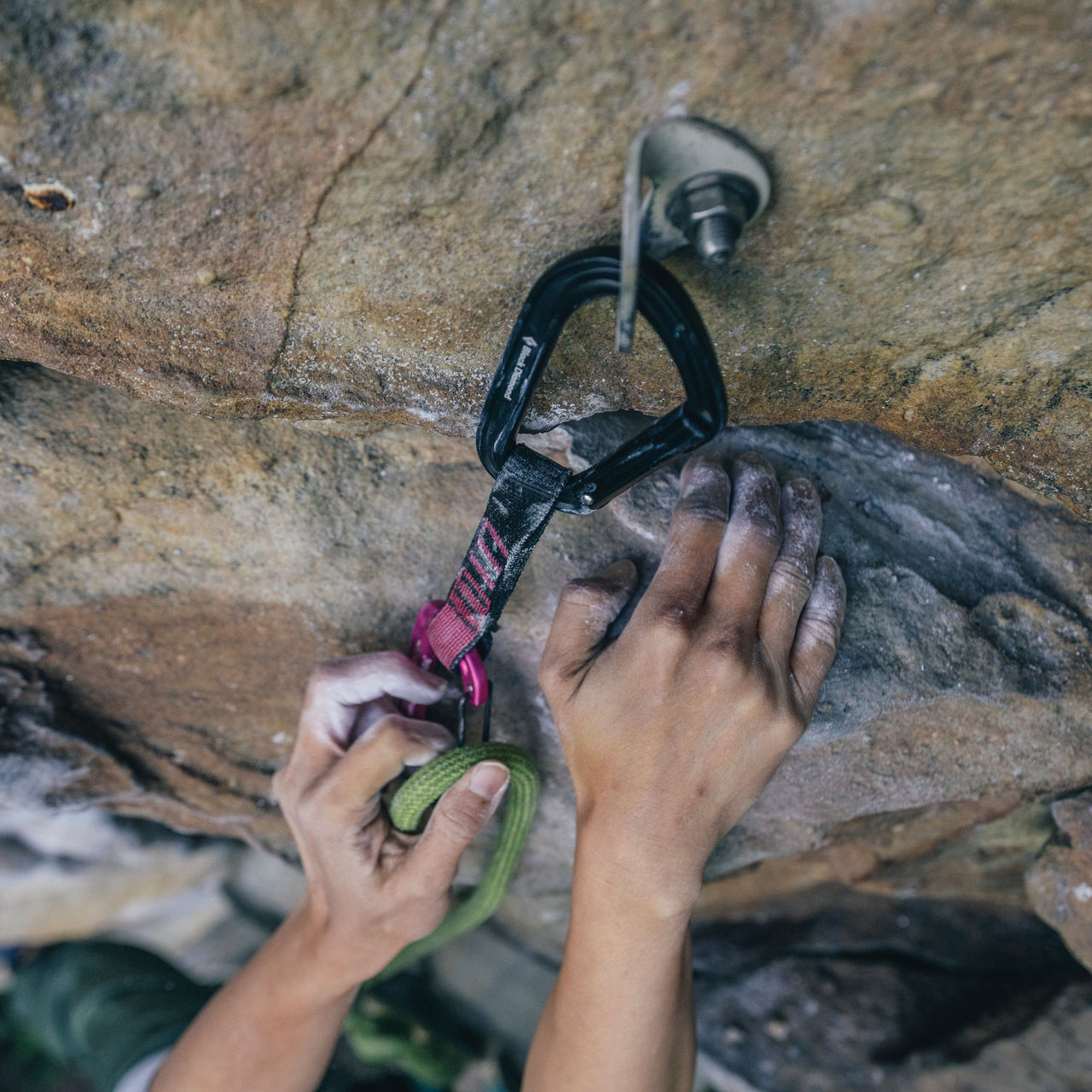 A detail shot of a climber clipping the rope on a draw