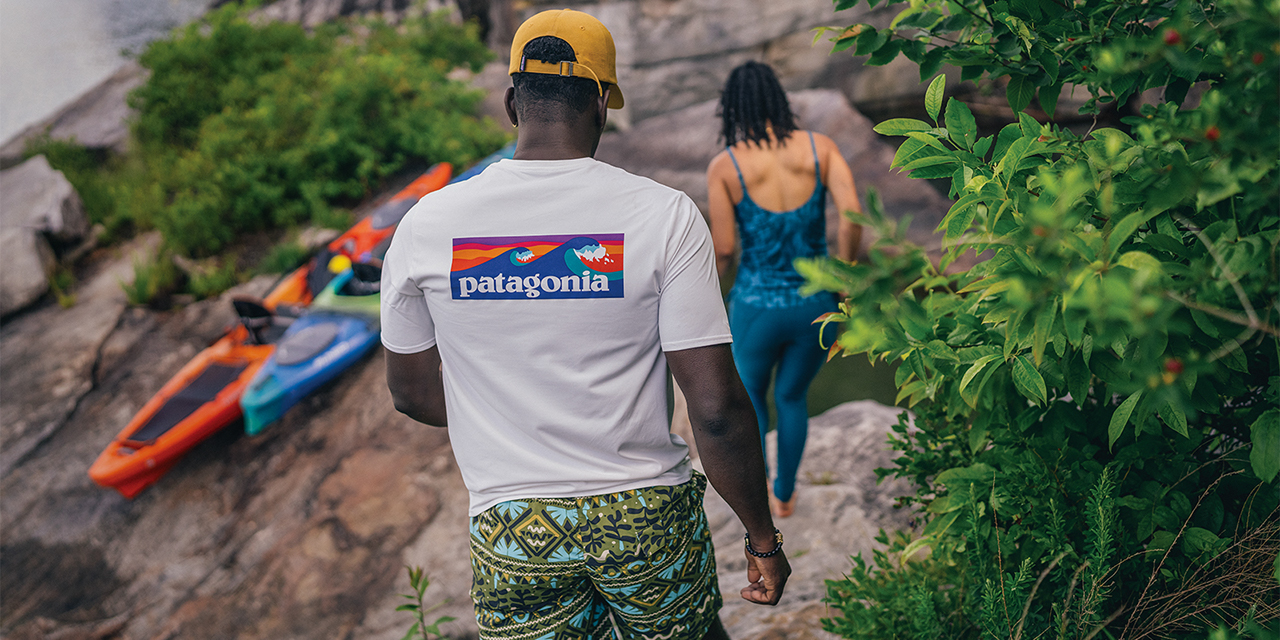 A man and woman walking down rocks next to a river.