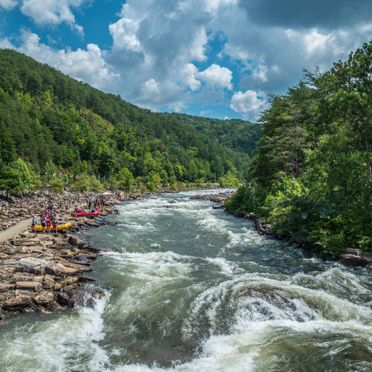 People along the Ocoee river on the rocks to whitewater kayak and raft at the Ocoee whitewater center in Tennessee on a sunny day in late summertime