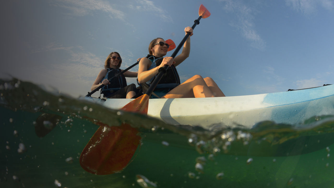 Two young women paddling blue kayak