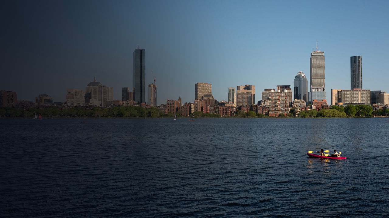 Two people kayak with the boston skyline