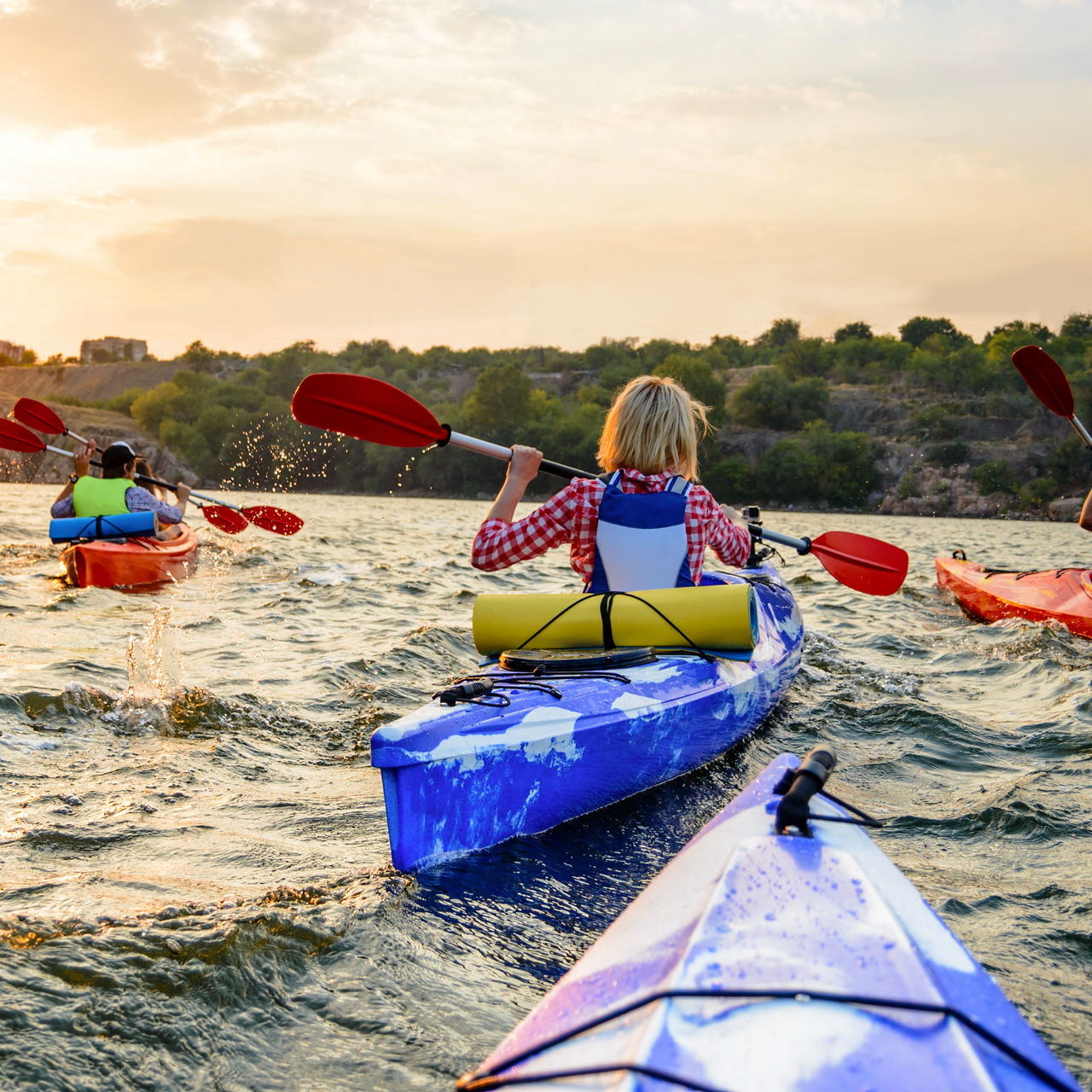 Friends Paddling Kayaks on the Beautiful River or Lake near High Rock under the Dramatic Evening Sky at Sunset.