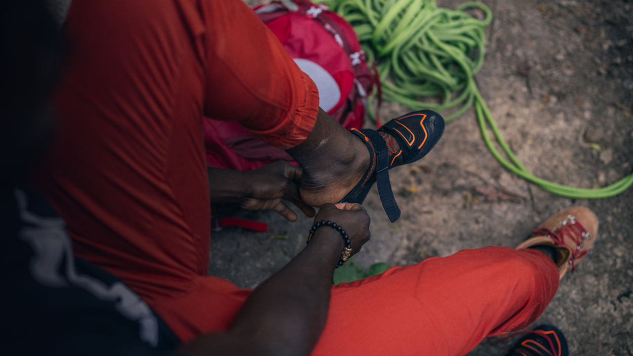 A man gets ready to climb by putting on climbing shoes