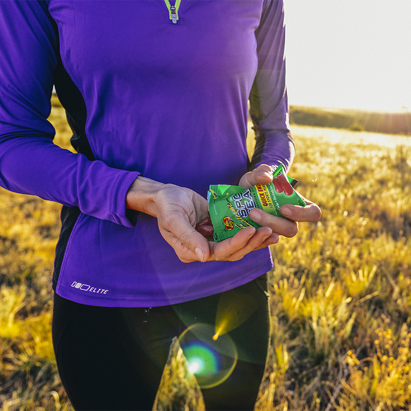 A woman eats nutrition gummies at sunrise on the trails of Green Mountain near Denver, Colorado.