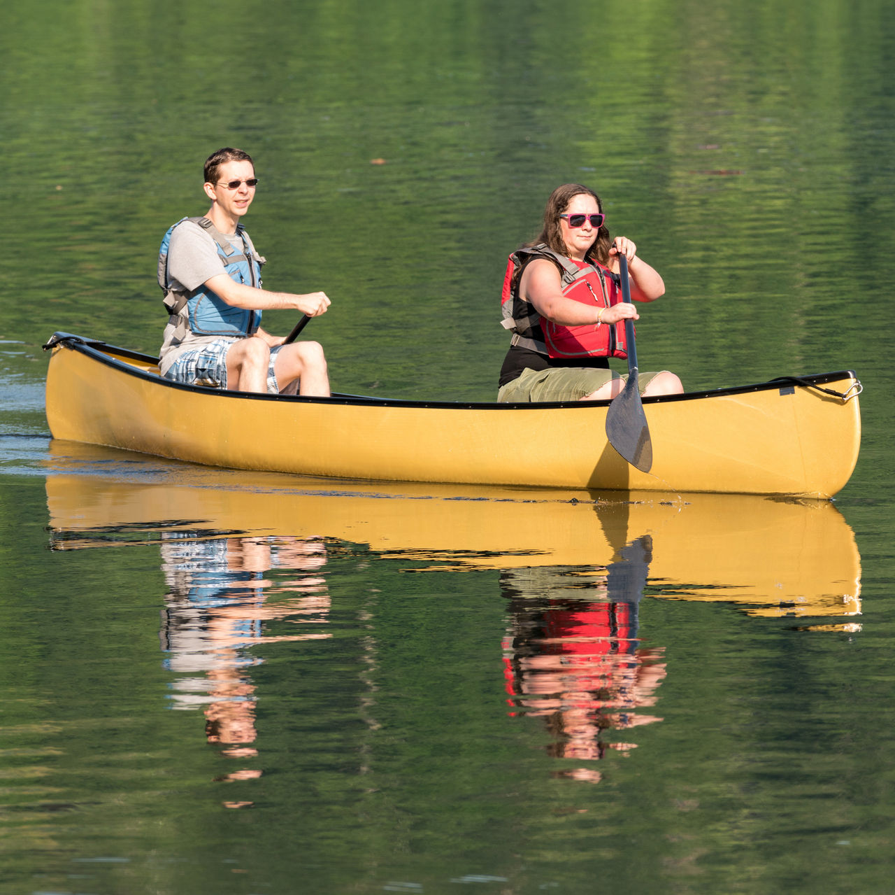 Two people paddling in yellow canoe 