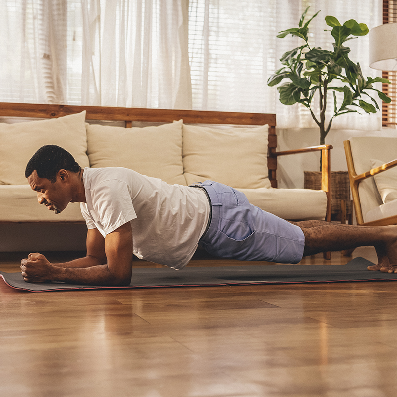 A man does a plank exercise in his living room