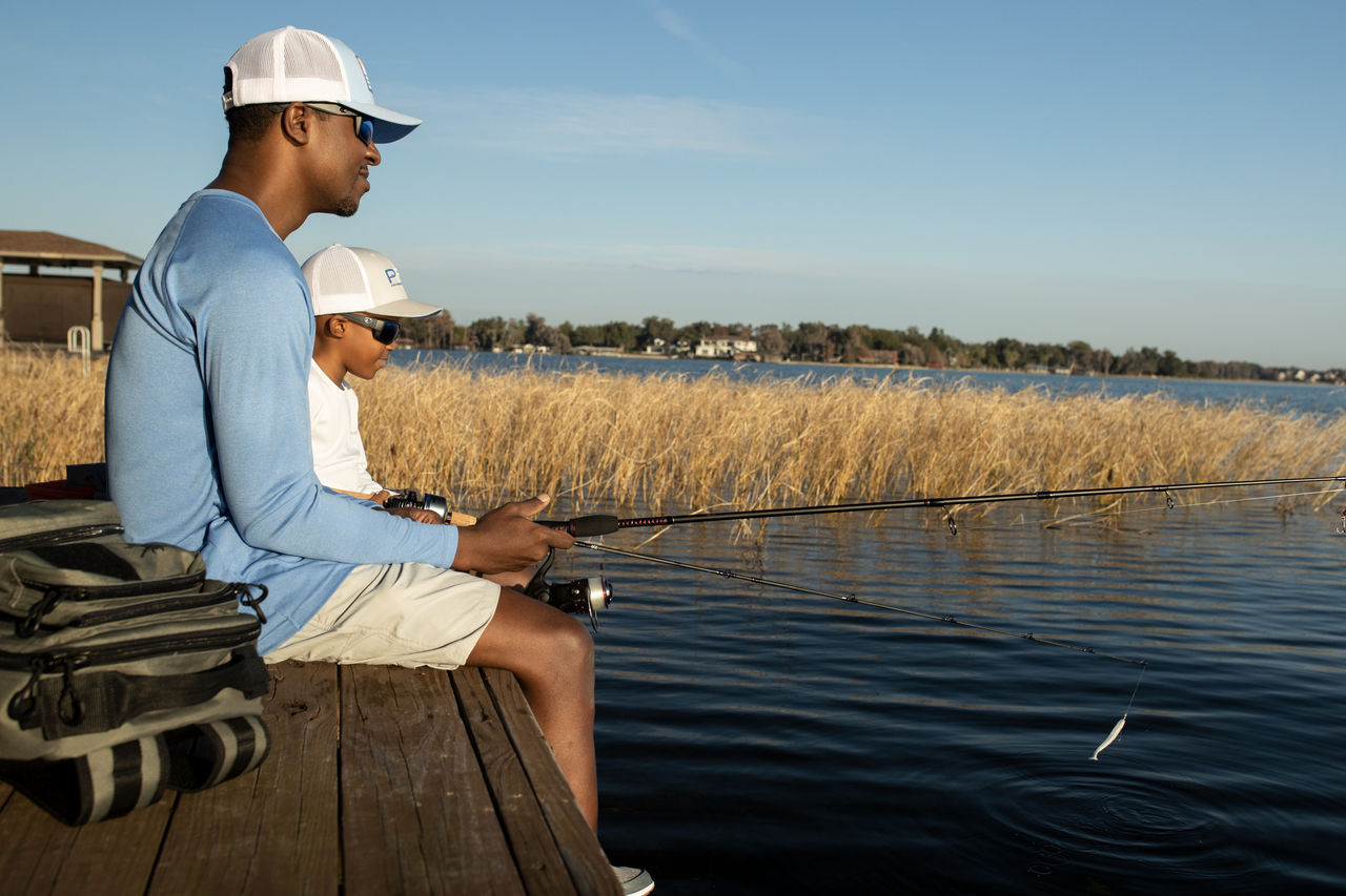 A father and son sit on a dock and fish