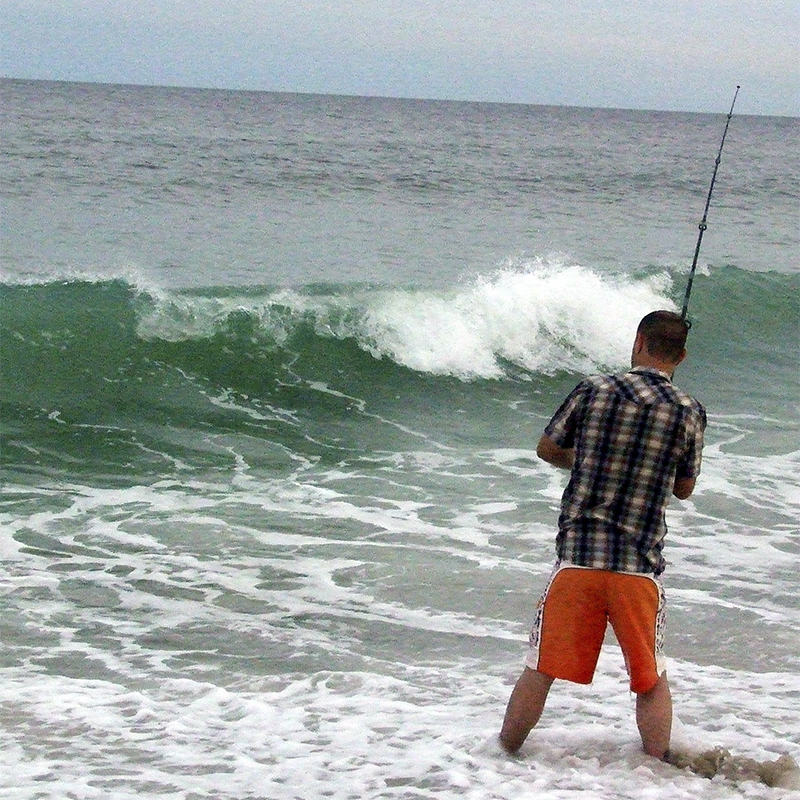 A person surf casts from the beach
