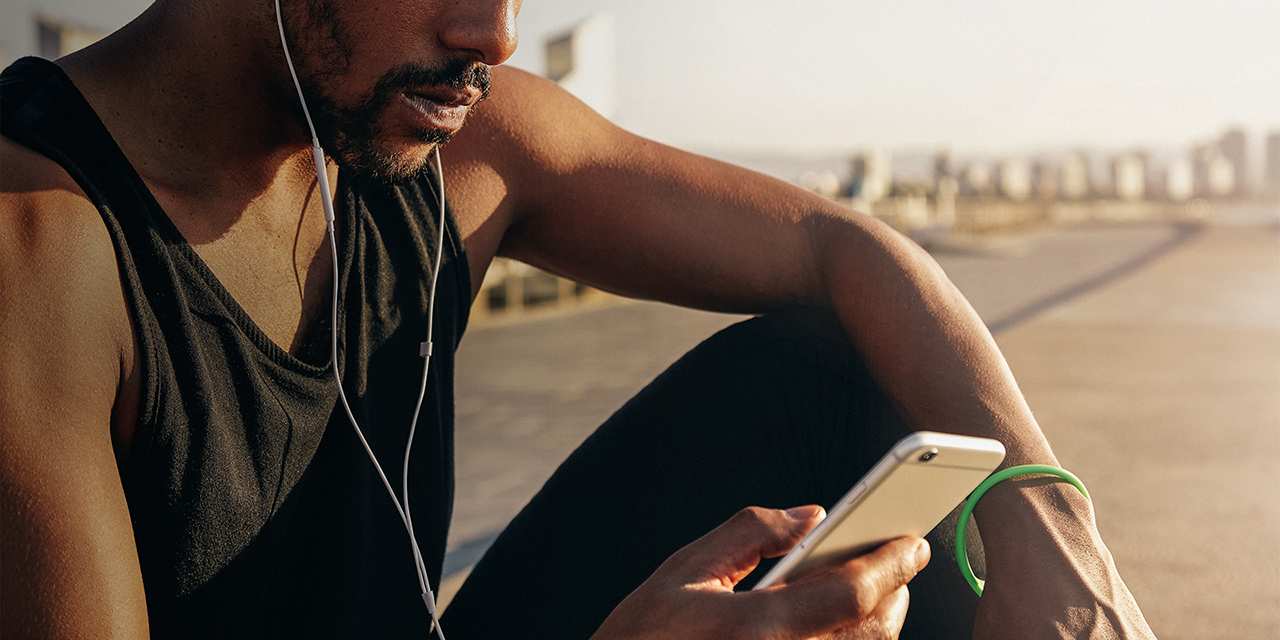 A man checks his phone outside on a break from running