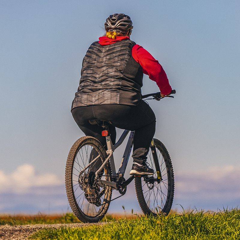 A woman riding a bicycle outdoor in the park. 