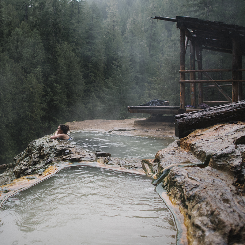 A woman soaks in a Umpqua hot spring overlooking the Umpqua National Forest 