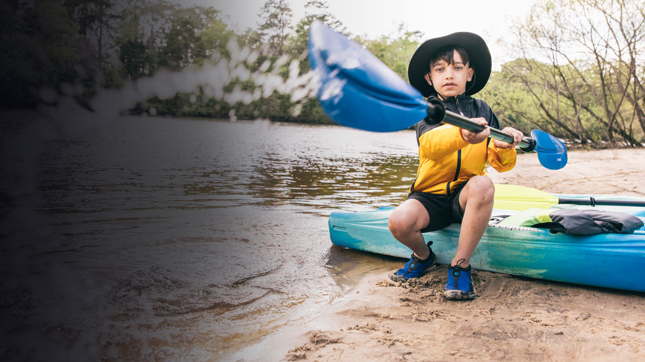 A kid plays with a kayak paddle