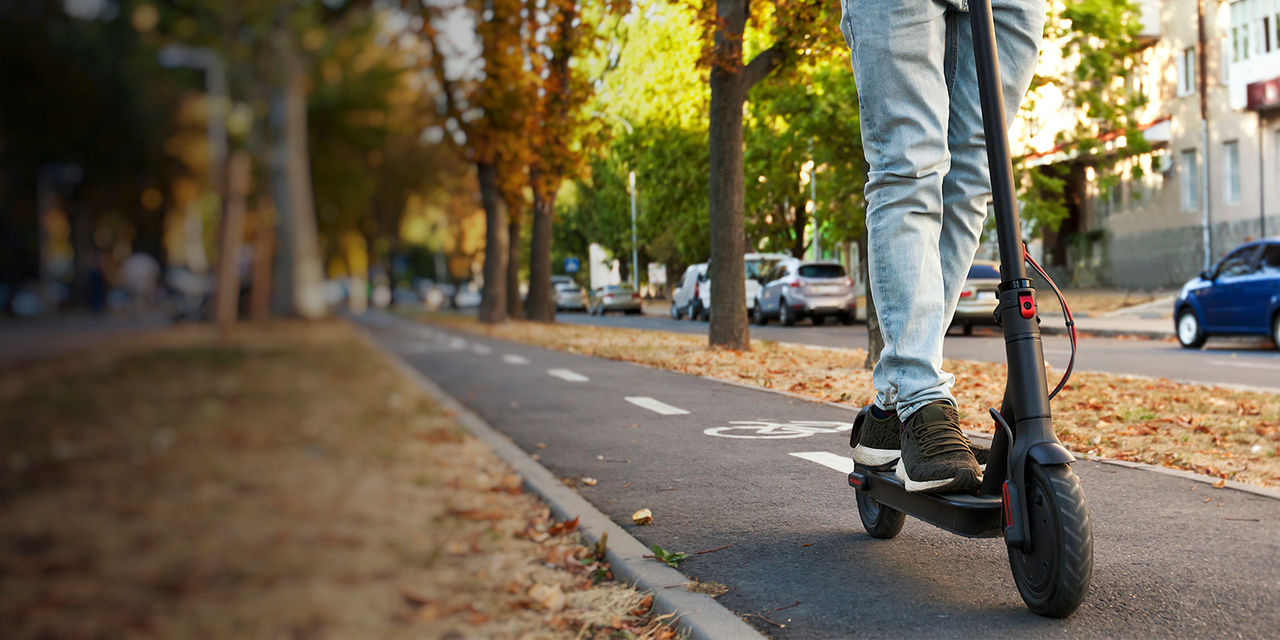 A person rides an electric scooter through the city by the pathways