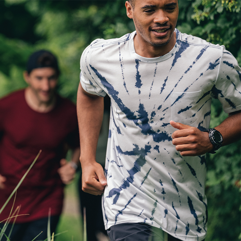 Runners on a trail wearing a tie-dye tee and red tee