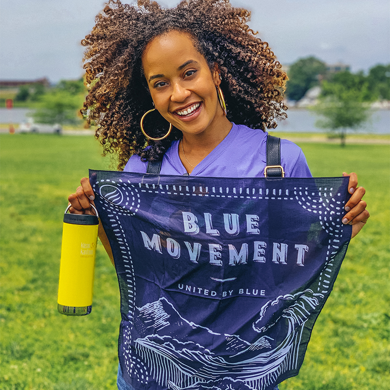 A woman holds a bandana for United By Blue