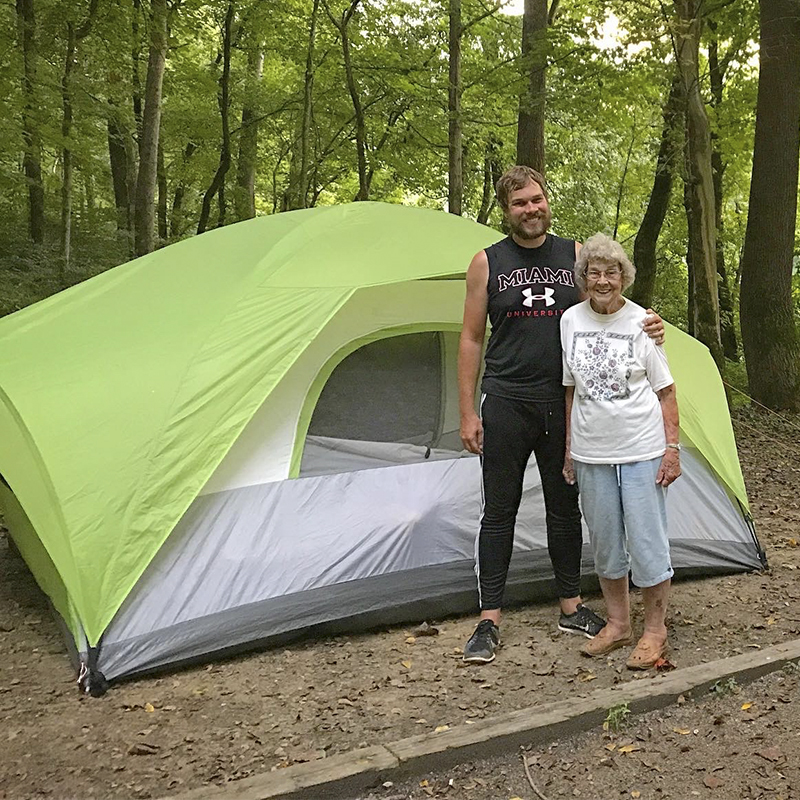 Grandma Joy and Brad Ryan pose in front of a tent