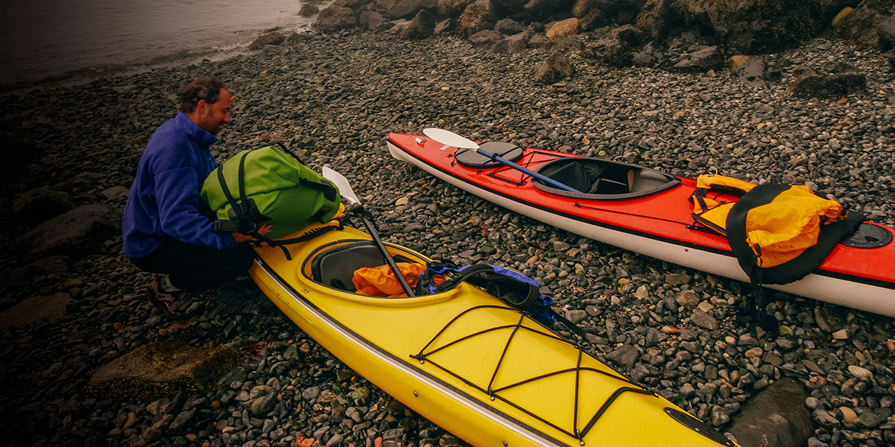 A man loads up his kayas to head out into the fog on Strawberry Island, San Juan Islands, Washington.