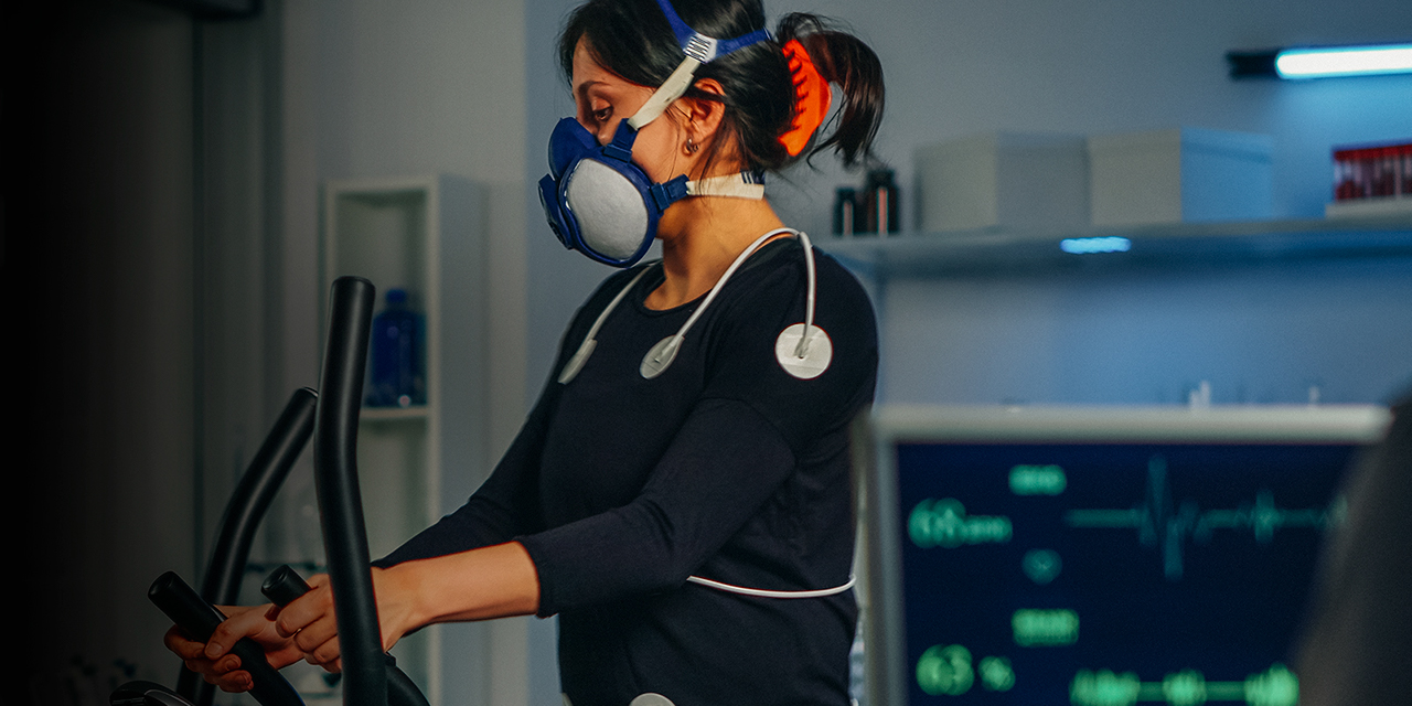 A woman uses body sensors, electrodes and mask measuring cardiac rhythm. and VO2 max