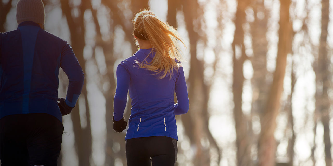 The backs of two runners on a winter path