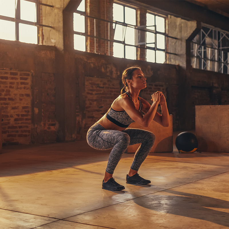 A woman does an air squat in a gym